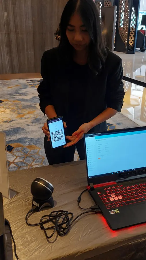 Petugas menampilkan QR code peserta ke sistem check-in